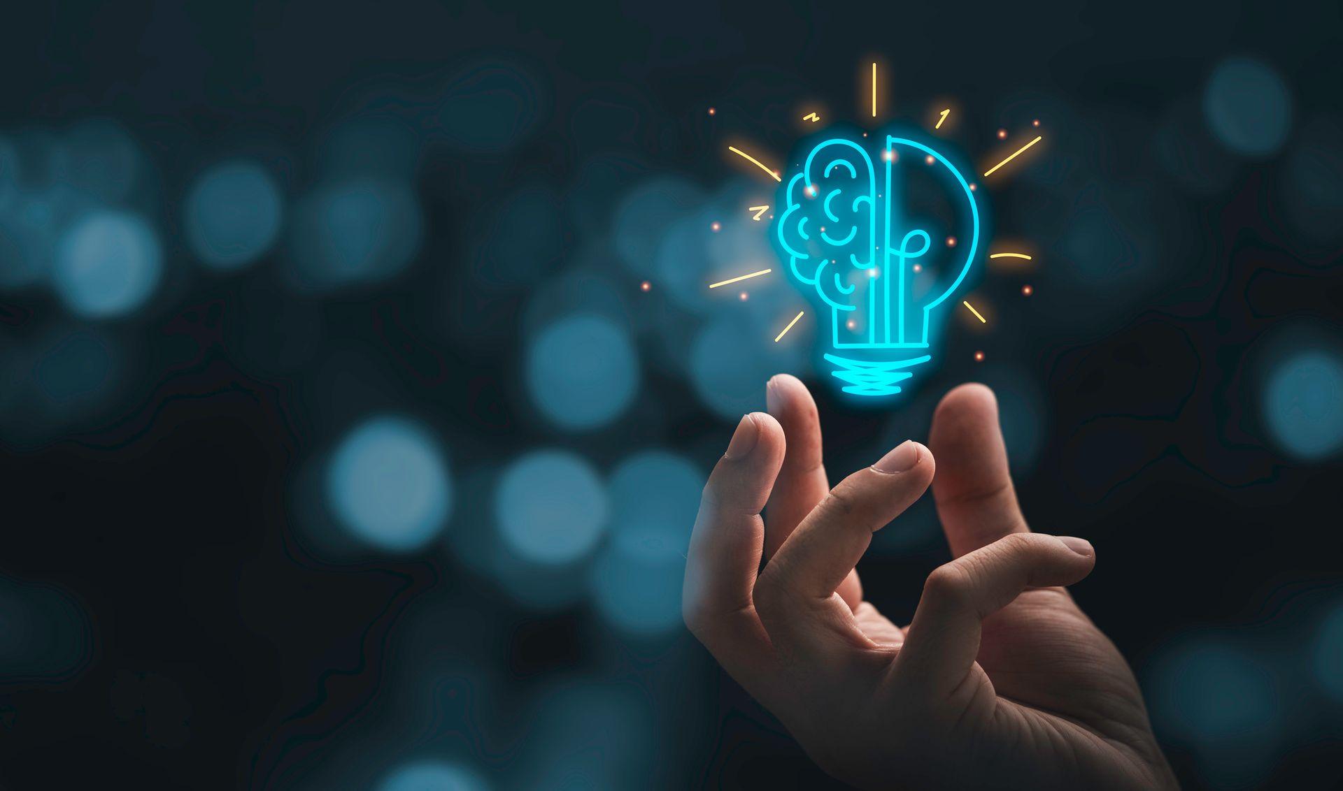 Hand holding a glowing lightbulb illustration with brain, symbolizing creativity and innovation.