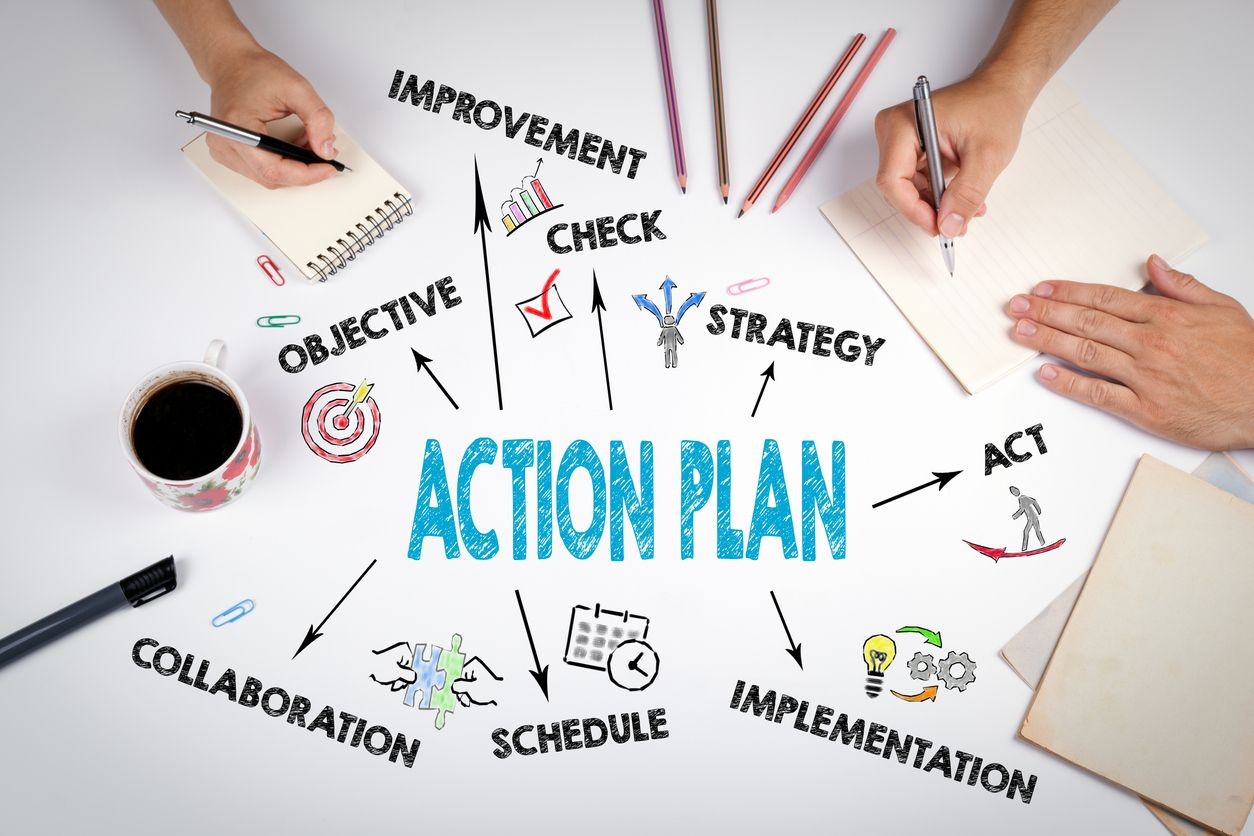 Brainstorming session with hands writing next to action plan keywords and icons on a white table.